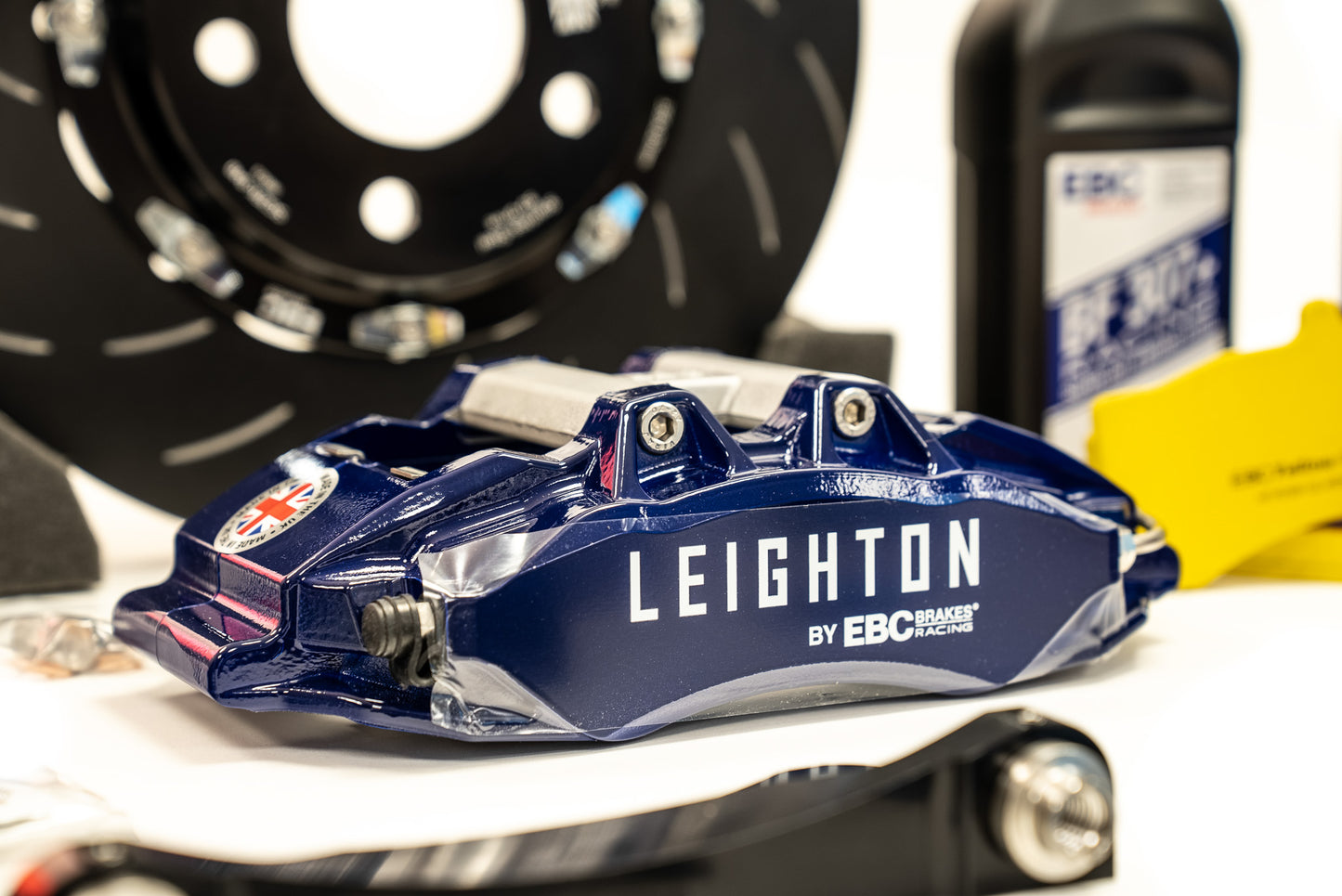 Close-up of a stylish alloy wheel with a geometric design, showcasing a black tire and a green "LEIGHTON" logo on a blue vehicle.