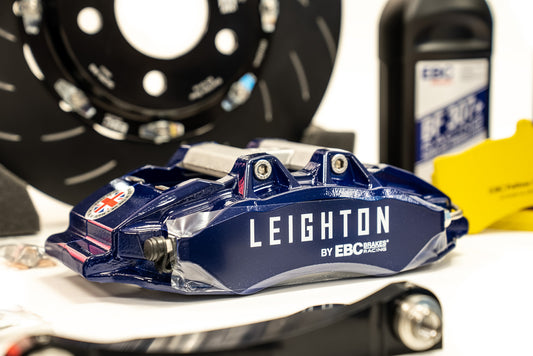 Close-up of a stylish alloy wheel with a geometric design, showcasing a black tire and a green "LEIGHTON" logo on a blue vehicle.